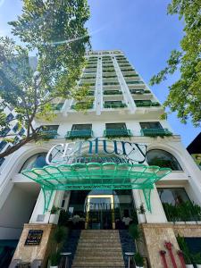 a tall white building with a sign on it at Century Hotel Da Nang in Da Nang +69 photos