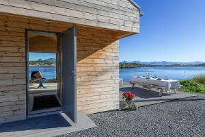 Una casa de madera con una mesa y vista al agua. en Tiny Cabin In Vesterålen, en Bø i Vesterålen