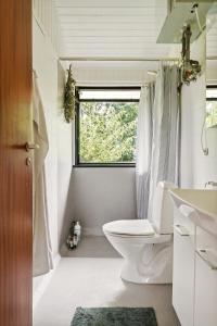 a white bathroom with a toilet and a window at The Red Summer House With The Lush Garden At Asnæs in Asnæs