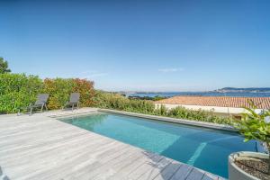 einen Pool mit zwei Stühlen auf einer Holzterrasse in der Unterkunft Villa With Panoramic Views Of Thau Lagoon in Bouzigues