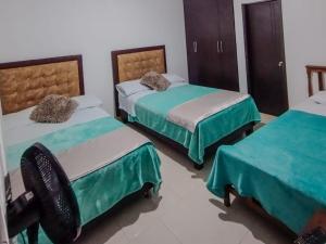 Zimmer mit 3 Betten und grüner und weißer Bettwäsche in der Unterkunft Hotel Guadalupe Home in Pereira