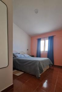 Un dormitorio con una cama y una ventana con cortinas azules. en La Nona, en El Carmen