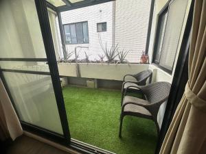 a balcony with two chairs and a window with green grass at Hour Roots in Tainan