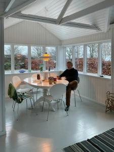 a man sitting at a table in a room at Cozy Red Cottage By Kalø Vig With Seaview in Hornslet