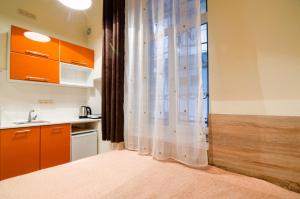 リヴィウにあるEconomy Apartment on Rappoporta 7a-1のキッチン(オレンジ色のキャビネット、シャワーカーテン付)