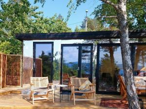 a house with glass doors and chairs on a deck at Unique Design And Beautiful View In Fjellstrand in Fjellstrand +10 photos