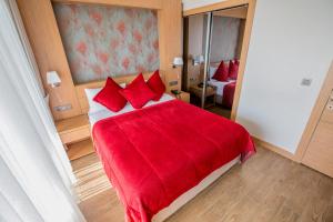 Hattusa Vacation Thermal Club Erzin في Erzin: غرفة نوم مع سرير احمر كبير مع مخدات حمراء