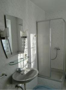a white bathroom with a sink and a shower at Penzion Buchmann in Františkovy Lázně