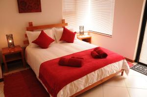 Un dormitorio con una gran cama blanca con almohadas rojas. en Moringa Gardens # 03 E, en Swakopmund