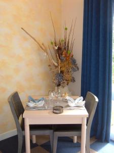 a white table with a vase of flowers on it at Le Parasol in Ars-en-Ré