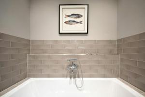 a bathroom with a tub with a picture on the wall at Getaway In East Frisia Elegant Lakeside Apartment in Friedeburg +14 photos