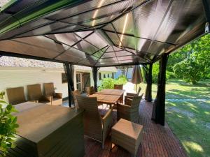patio con tavolo e sedie sotto un tetto di Charming Country House In Schleswig-Holstein a Fedderingen