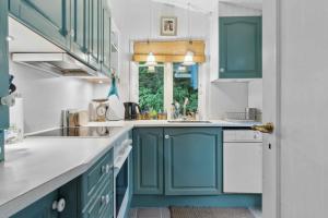 eine Küche mit blauen Schränken und einer Spüle in der Unterkunft Cozy Holiday Home Near The Beach And Nature in Frederiksværk