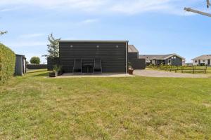 a black house with two chairs in a yard at Beautiful Home In As Vig, 100 M From The Beach in Sønderby