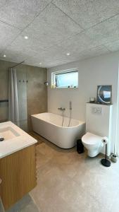 a large bathroom with a tub and a toilet at Modern Holiday Home Near Vesterløkken Beach in Tanderup