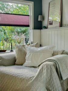 a bedroom with a bed with pillows and a window at Beach-Close Wooden Summer House In Tversted in Tversted