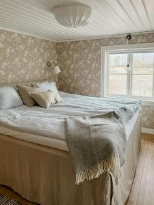 ein Schlafzimmer mit einem großen Bett mit Fenster in der Unterkunft Historic Cottage Near Wiredaholm in Aneby