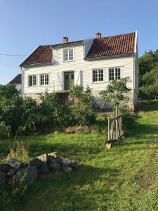 una casa blanca con una valla en el patio en Idyllic Farmhouse From 1840 With Sea View In Spind, en Farsund