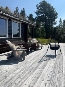 a wooden deck with a table and a swing at Mountain Cabin By Hundsåvatnet With Large Veranda in Fannrem