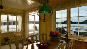 a dining room with a table and chairs and windows at Cabin With Sunset Views And Private Dock in Sandefjord