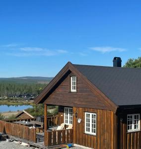 a log cabin with a deck and a lake at Family Cabin With Ski Inout At Furutangen in Vika