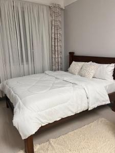 a bed with white sheets and pillows in a bedroom at The City escape Sabaki green estate - 15 minutes to JKIA and SGR in Marimbeti +16 photos
