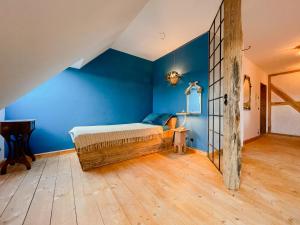 a bedroom with a bed with blue walls and a wooden floor at Cozy Holiday Apartment In The Manor House in Rambin +11 photos