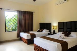 a hotel room with two beds and a window at Hotel Hacienda Izamal in Izamal