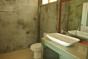 a bathroom with a sink and a toilet and a mirror at Bottle Beach 2 Bungalows in Bottle Beach