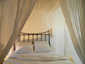 a bedroom with a canopy bed with white curtains at Avra Pahainas in Pachaina