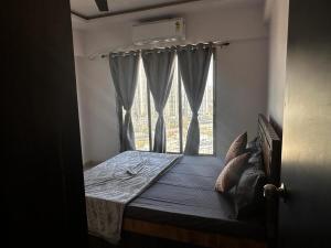 Schlafzimmer mit einem Bett und einem Fenster in der Unterkunft Skyline Oshiwara 2bhk-Andheri in Mumbai