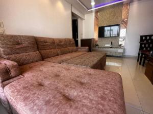ein Wohnzimmer mit einem braunen Sofa und einem Tisch in der Unterkunft Skyline Oshiwara 2bhk-Andheri in Mumbai