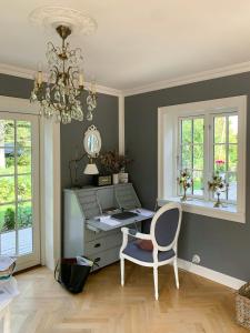 an office with a desk and a chair and a chandelier at New England Inspired Holiday Home In Rågeleje in Vejby