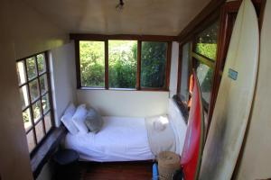 a small bedroom with a bed and a surfboard at Shack on Supers in Jeffreys Bay