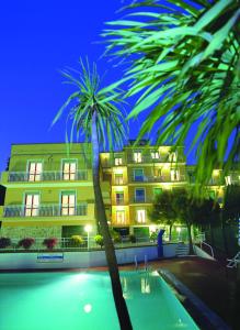 皮耶特拉利古雷的住宿－莫瑞樂公寓式酒店，一座棕榈树在游泳池前的建筑