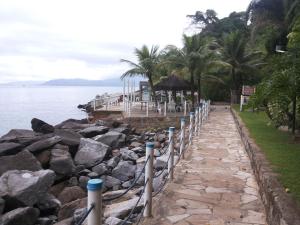 a walkway next to the water with rocks at Apartamento Porto Real Brites in Mangaratiba