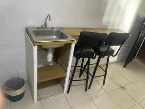 a sink and two black stools under a sink at Cuarto Longanizo -privado, céntrico- Casa de Teru in Tapachula