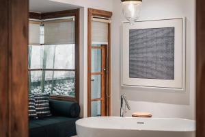 baño con bañera y ventana con sofá en Kharista Villas & Retreat by Ekosistem, en Canggu