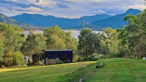 a building in a field with a lake and mountains at Moogie Pod - Trendy tiny getaway in Moogerah