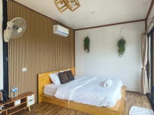 a bedroom with a bed with white sheets and a fan at ดอกฟ้า ม่อนแจ่ม in Mon Jam