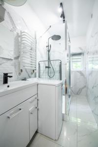 a white bathroom with a shower and a sink at Apartament Lipowa 26 in Gliwice +49 photos