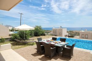 patio ze stołem i krzesłami oraz basenem w obiekcie Athoniki Villas w mieście Kalathos