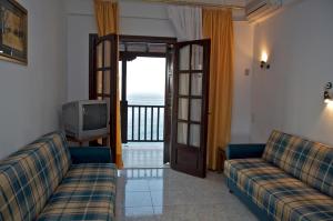 a living room with two couches and a television at Karaoulanis Beach in Agios Ioannis Pelio