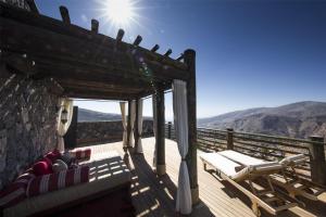 a deck with lounge chairs and a view of the mountains at Alila Jabal Akhdar in Al Khuţaym