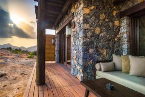 a porch of a house with a stone wall and a couch at Alila Jabal Akhdar in Al Khuţaym