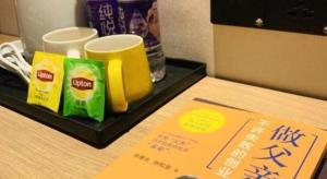 Una mesa con una bandeja con tazas y un cartel encima. en GreenTree Inn Express Qingdao Laixi High-Speed Railway Station Shenzhen Road, en Laixi