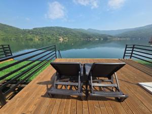 a pair of chairs sitting on a wooden deck overlooking a lake at Villa Razlicak - Jezero Lake Perucac in Perućac
