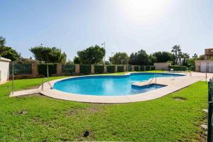een groot zwembad in een tuin met gras bij BLUE BEACH HOUSE, Retamar, Cabo de Gata in Almería