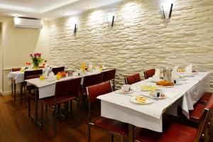 um restaurante com mesas e cadeiras brancas e uma parede de pedra em Hôtel Ambassadeur em Paris