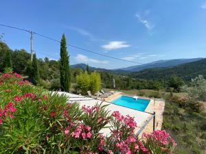a villa with a swimming pool and mountains in the background at Villa Férus Piscine chauffée chambres d'hôtes in Buis-les-Baronnies